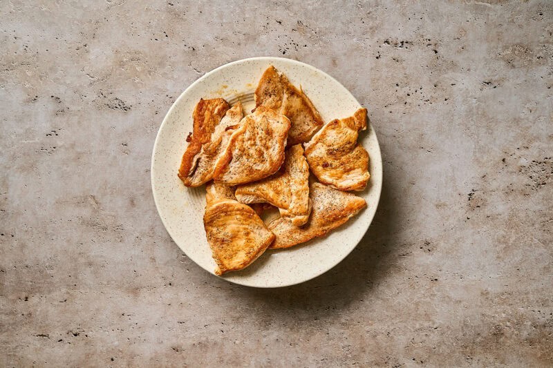 Cooked chicken cutlets on a white plate.