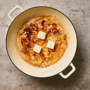 Cubes of butter melting in a skillet with chicken juices.