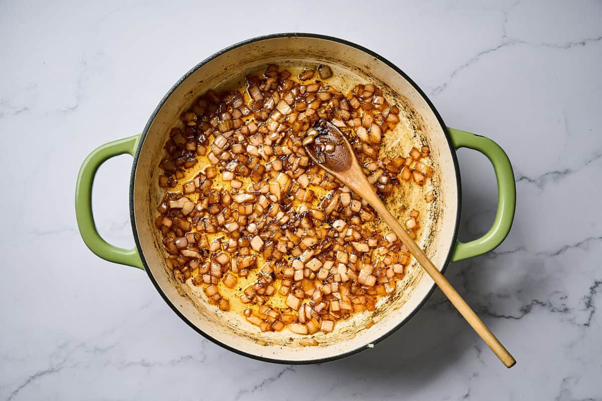 Sautéed onion and garlic in a skillet over a white marble surface.