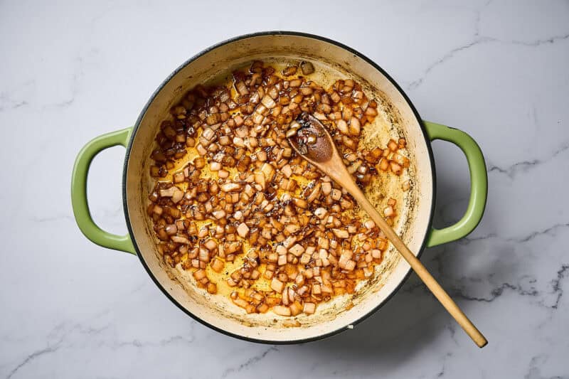 Sautéed onion and garlic in a skillet over a white marble surface.