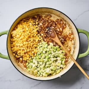 Corn and lime beans added to a skillet with onions.