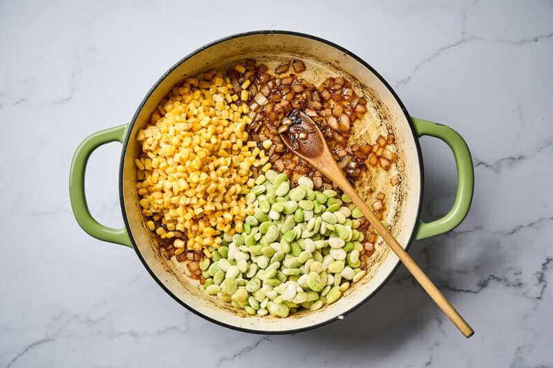 Corn and lime beans added to a skillet with onions.