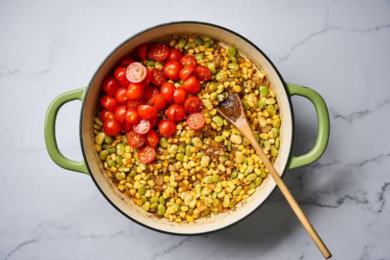 Fresh cherry tomatoes in a skillet of corn and lima beans.