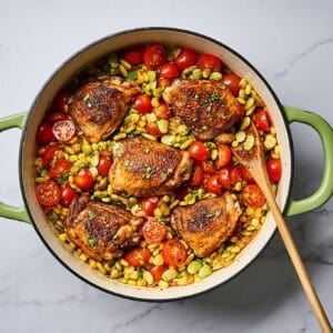 Chicken thighs and corn succotash in a skillet, garnished with cilantro.