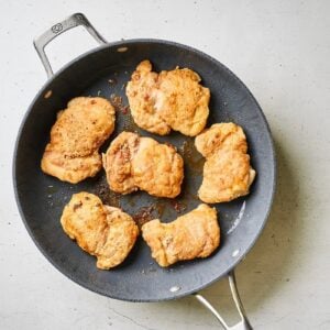 Chicken thighs browned in a skillet.