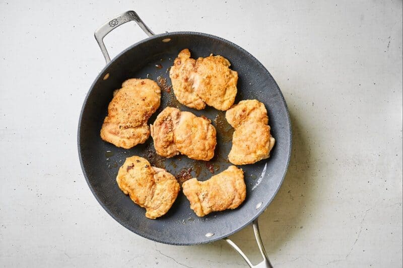 Chicken thighs browned in a skillet.
