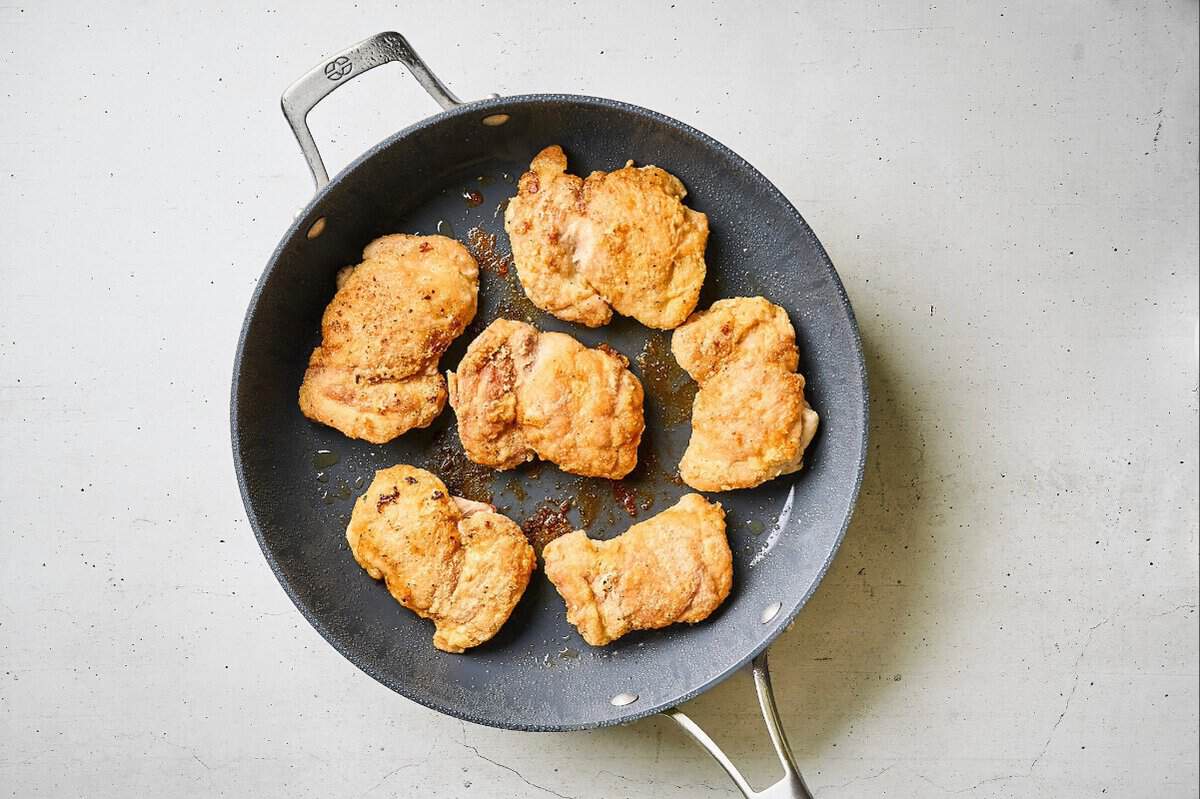 Chicken thighs browned in a skillet.