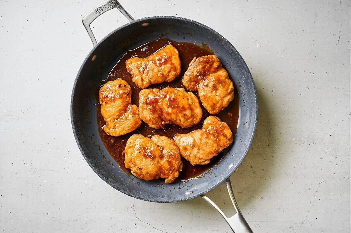 Chicken thighs in the sauce in a skillet.