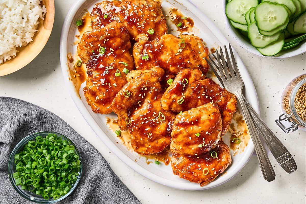 Shoyu chicken garnished with sesame seeds and sliced green onions.