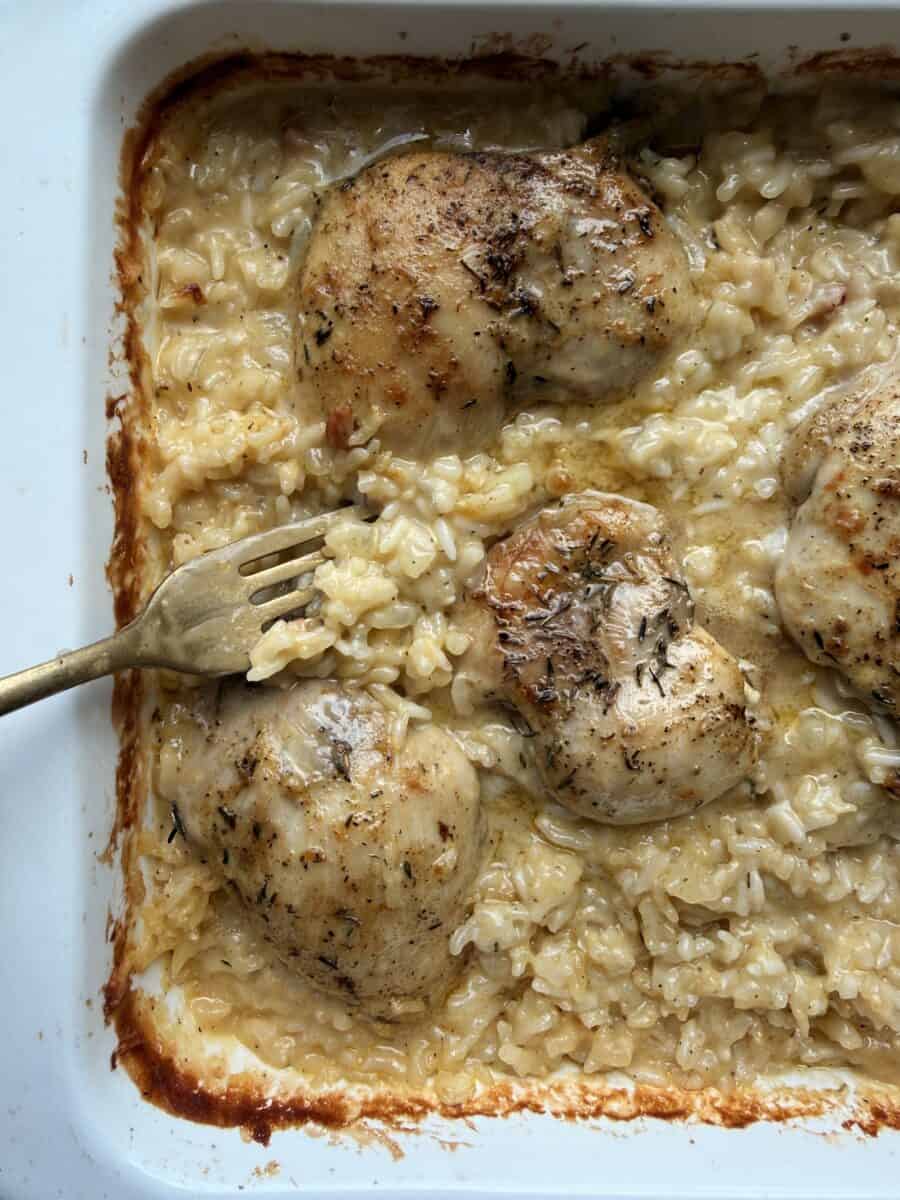 Digging into chicken thigh and rice casserole with a fork.