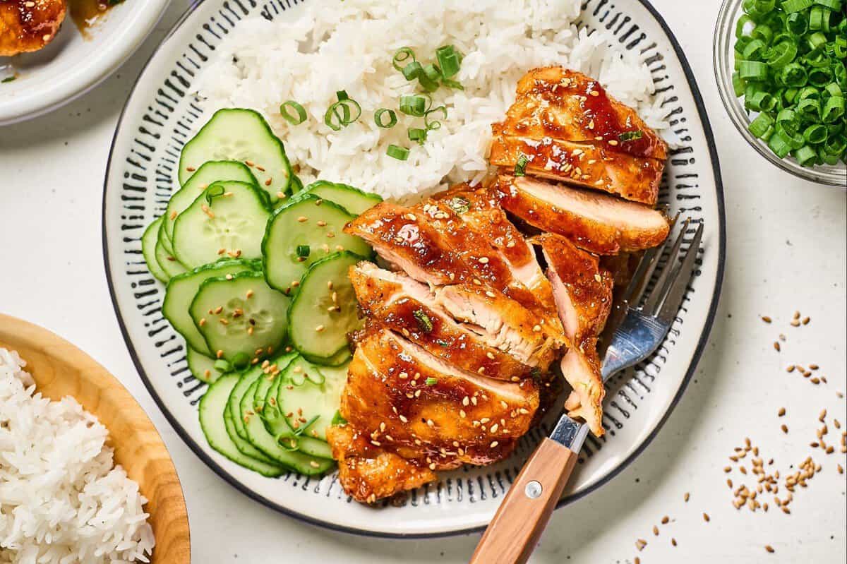 Shoyu chicken served with rice and sliced cucumber.