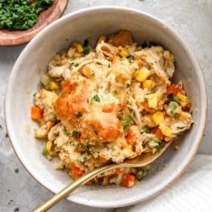 A white bowl of chicken cobbler with a fork.