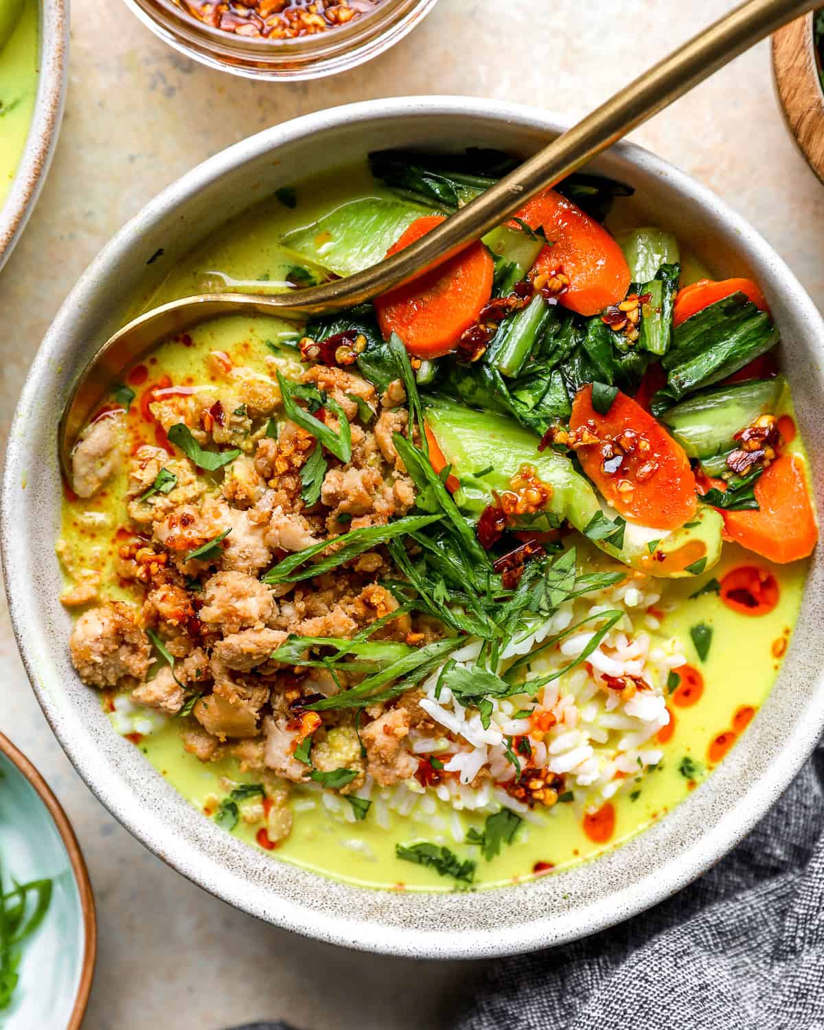 A ground chicken broth bowl filled with rice, carrots, and creamy coconut milk broth.