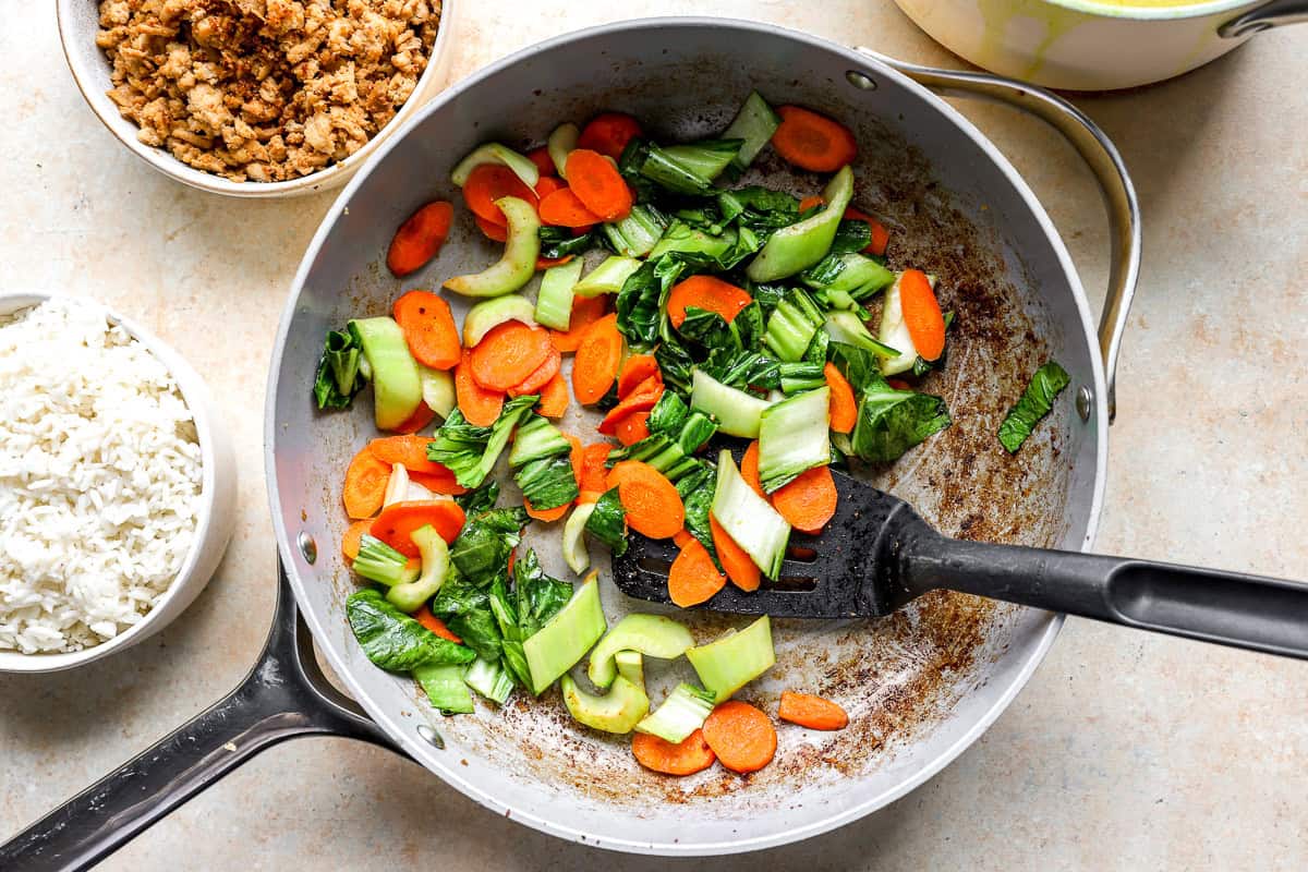 Sautéing carrots and bok choy in a skillet.