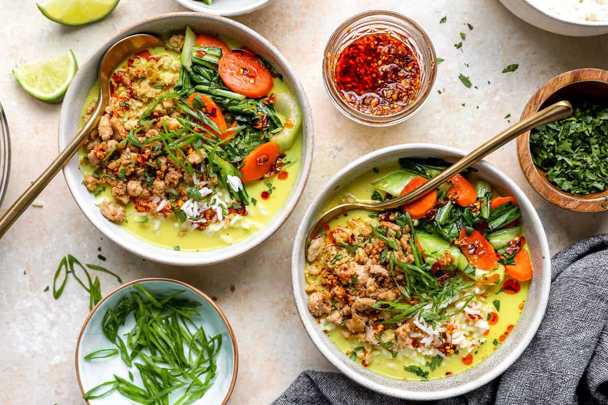 Two ginger coconut milk broth bowls topped with ground chicken, carrots, and bok choy.