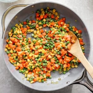 Stirring frozen mixed vegetables in a pan.