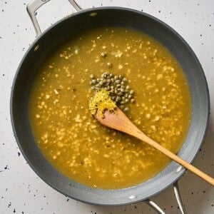 Adding capers to piccata sauce.