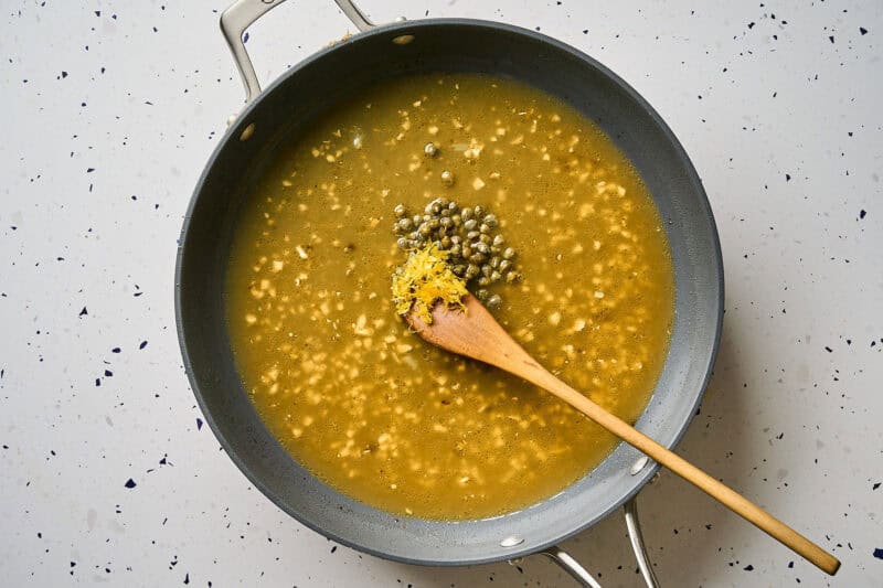 Adding capers to piccata sauce.