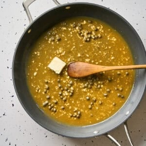 A cube of butter in a pan of piccata sauce.