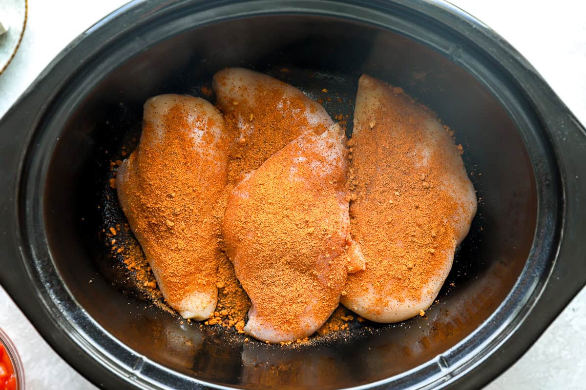 Seasoning added to chicken breasts in a slow cooker.