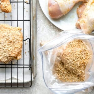Dredging chicken in seasoned breadcrumbs.