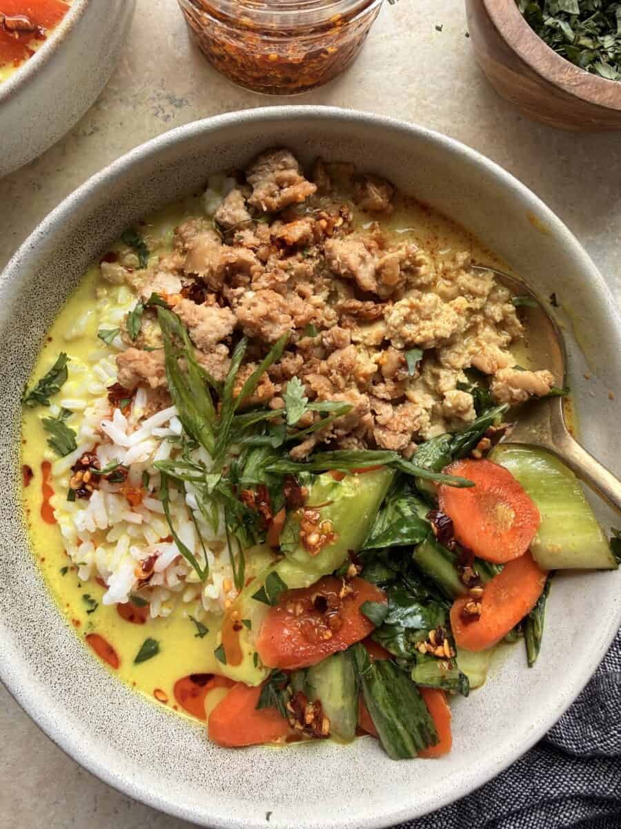 A creamy ginger coconut broth bowl filled with ground chicken, rice, and veggies.