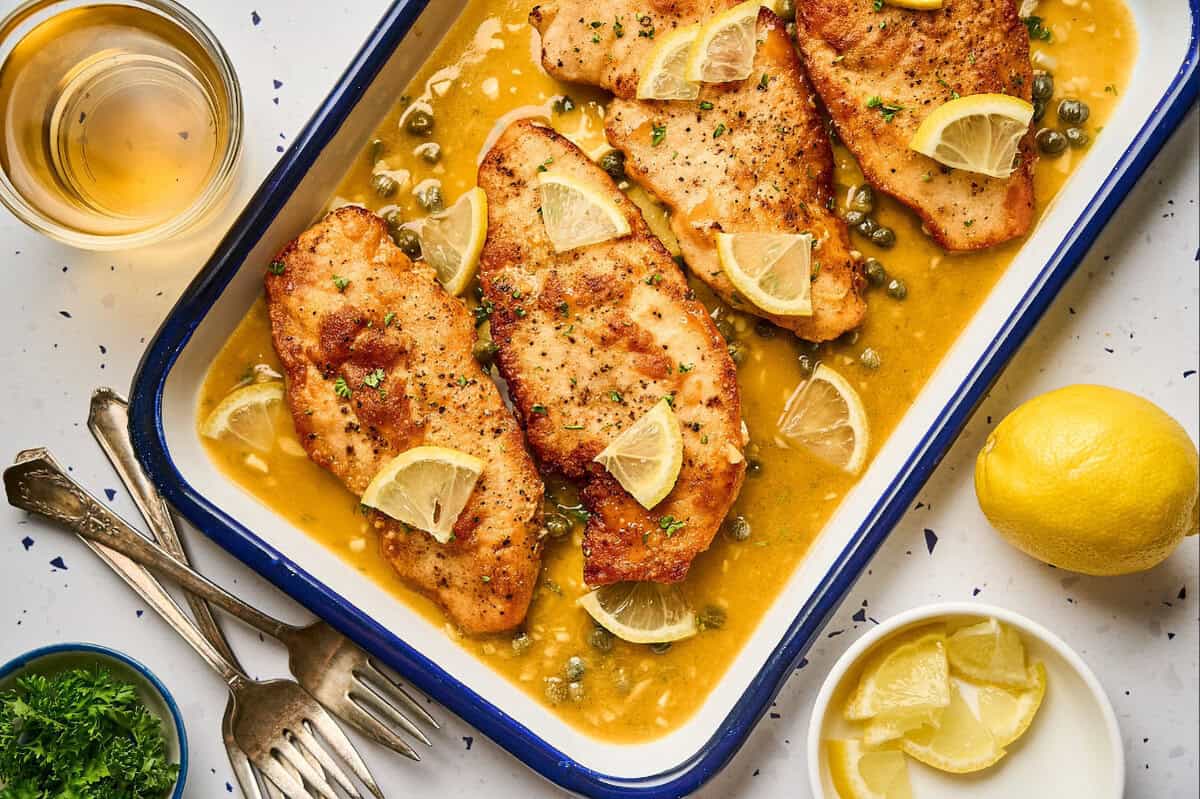 Lemon chicken scallopini in a serving tray garnished with lemon and parsley.