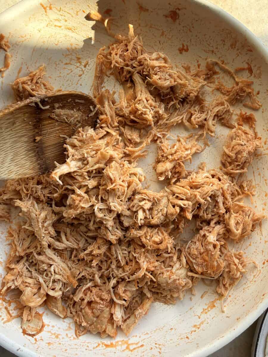 Cooking buffalo shredded chicken in a skillet.