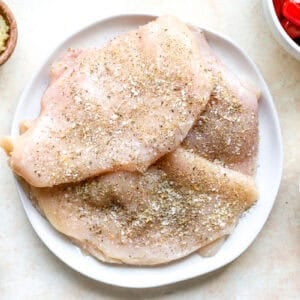 Raw seasoned chicken breasts.
