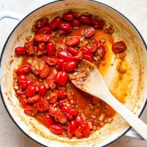 Cooking grape tomatoes in a pan.