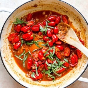Tomatoes and basil cooking in a pan.