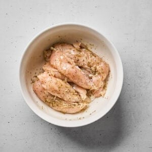 Chicken tenders marinating in Greek marinade.