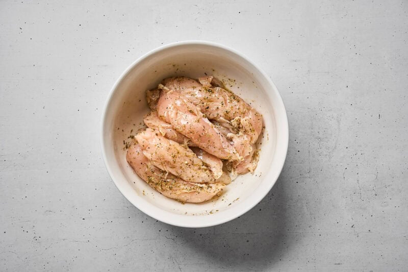 Chicken tenders marinating in Greek marinade.