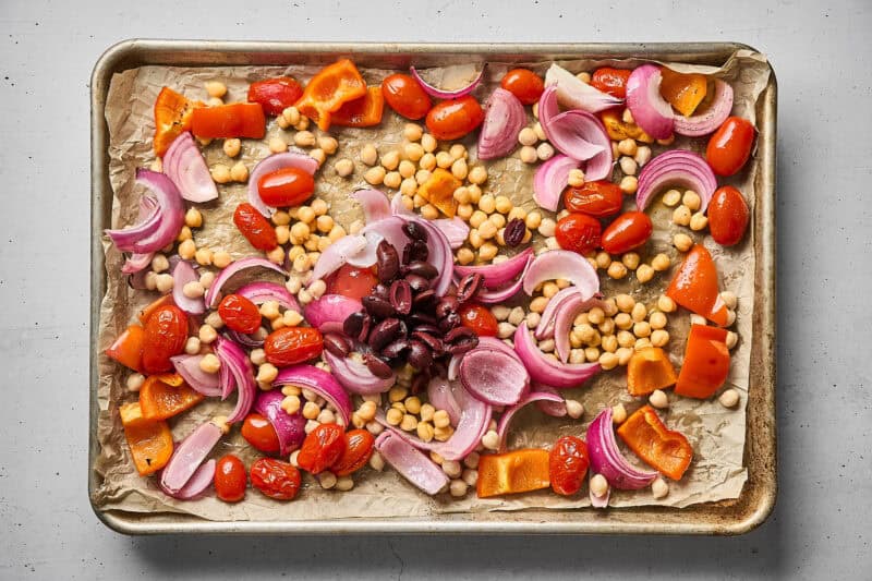 Kalamata olive added to the sheet pan with chickpeas and veggies.