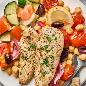 A plate of Greek chicken tenders served with chickpeas and Mediterranean veggies.