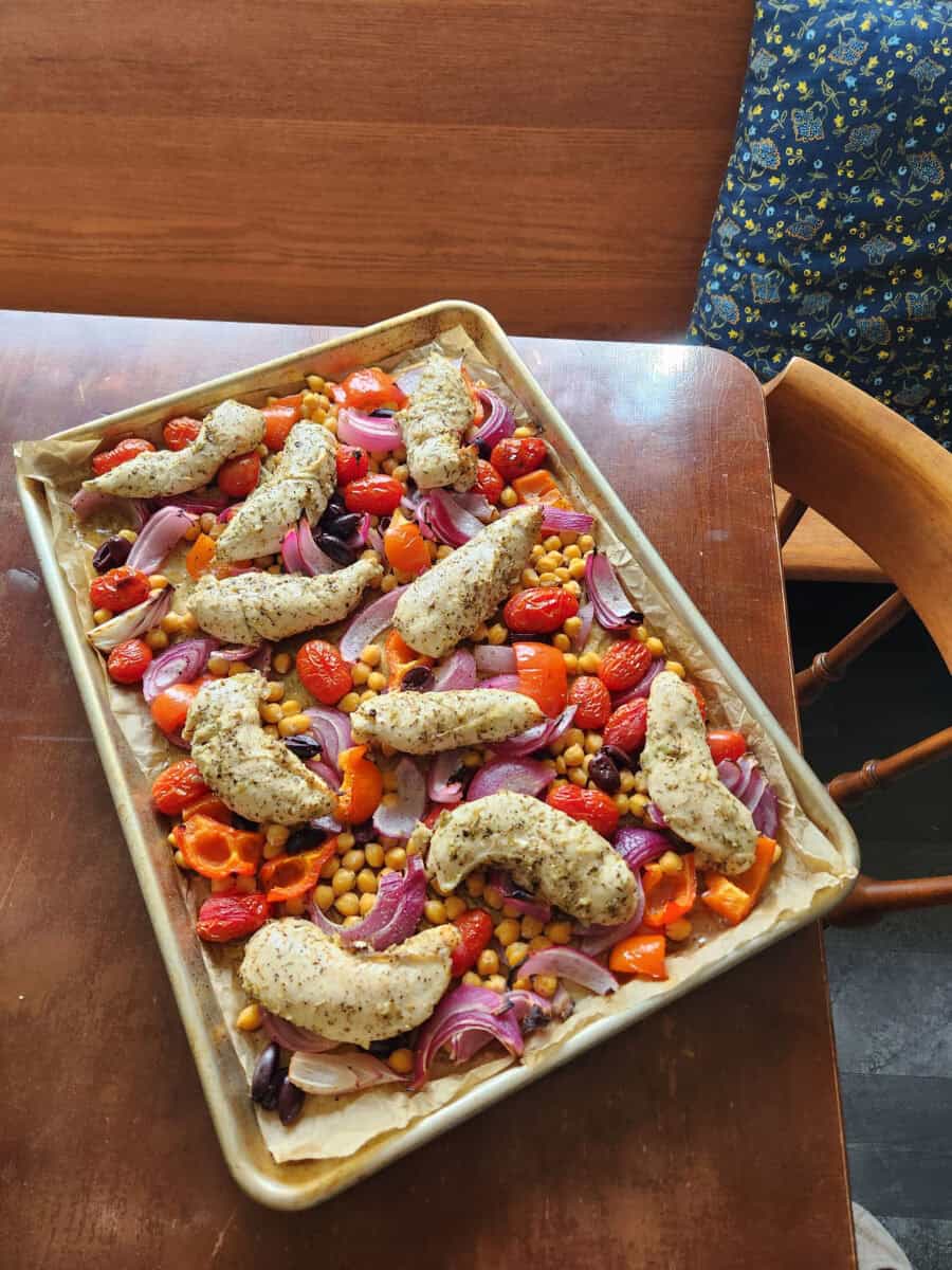 Sheet pan Greek chicken, chickpeas, and veggies on a table.