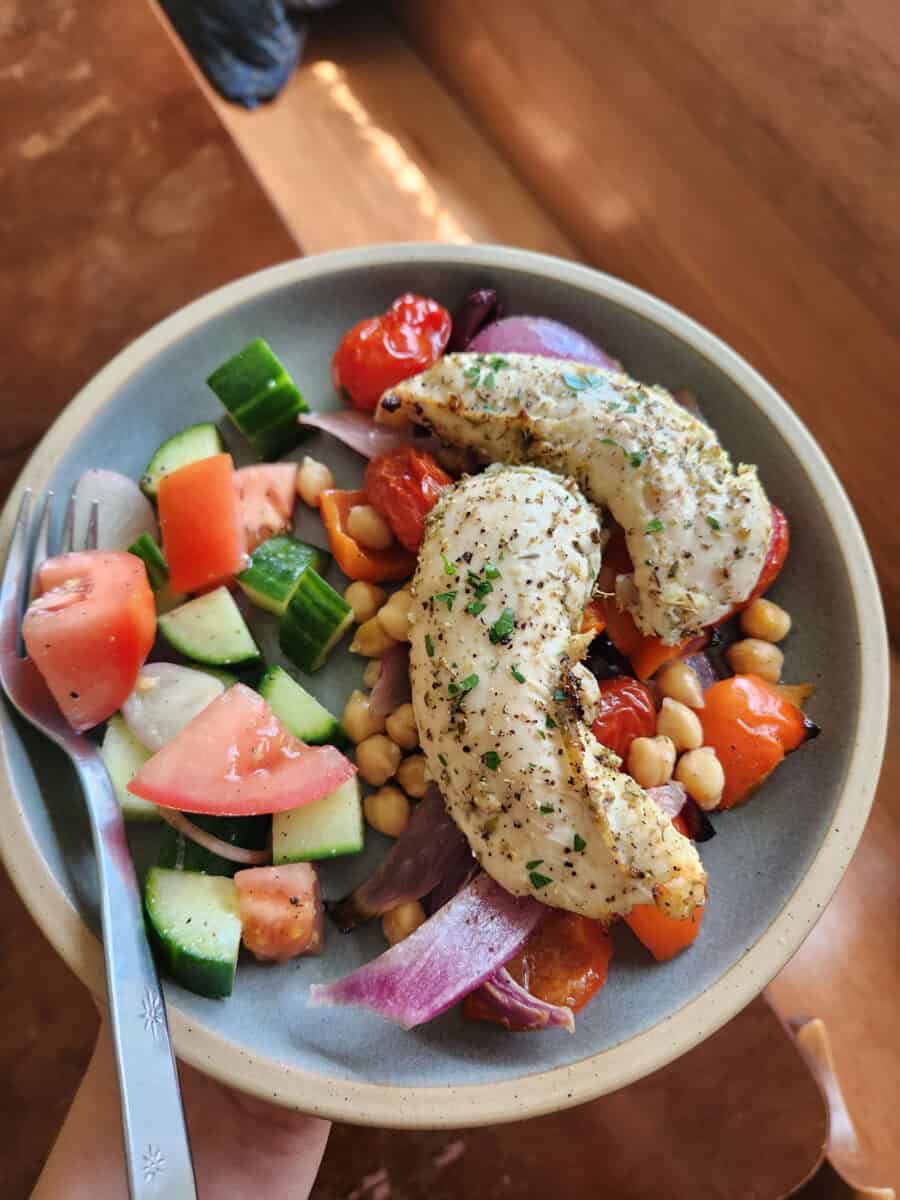 Holding up a serving of Greek chicken and chickpeas sheet pan meal.