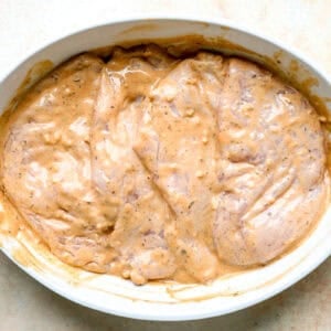 Raw chicken breasts marinating in tahini sauce.