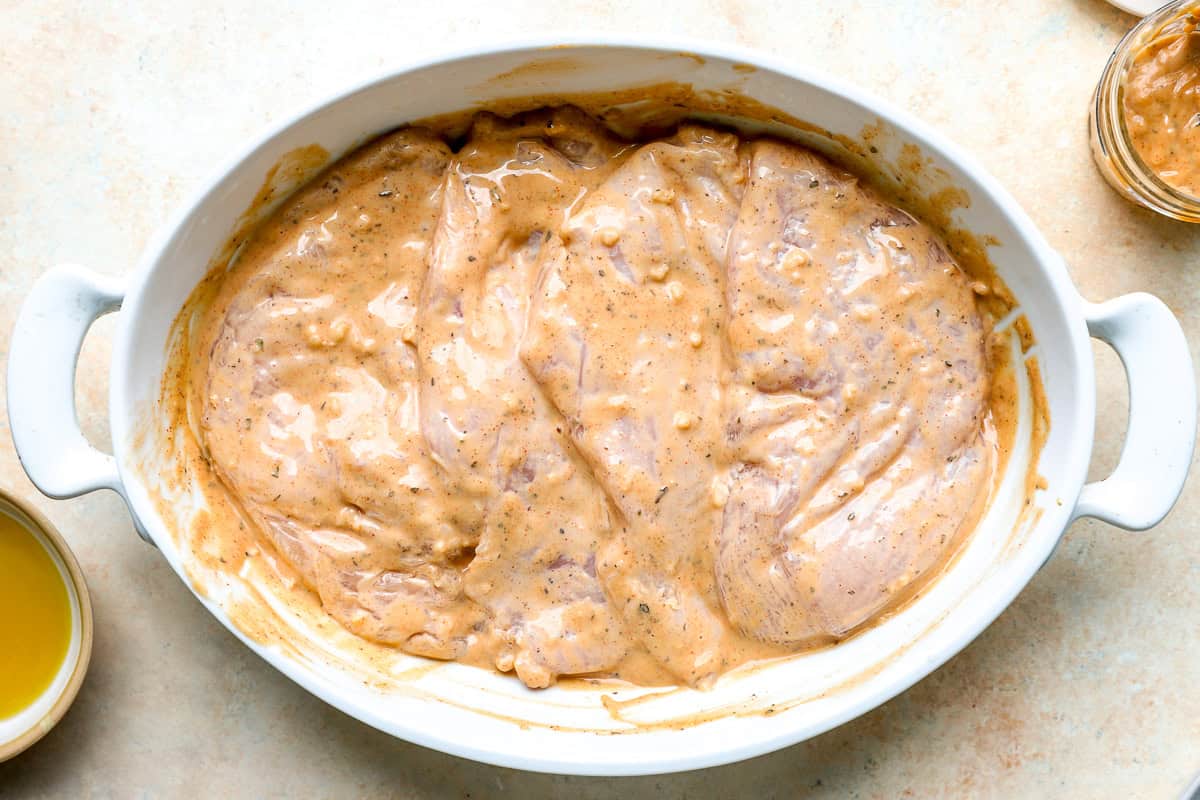 Raw chicken breasts marinating in tahini sauce.