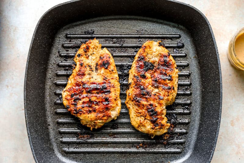Cooked chicken breasts on a grill pan.