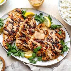 A plate of grilled chicken and tahini sauce.