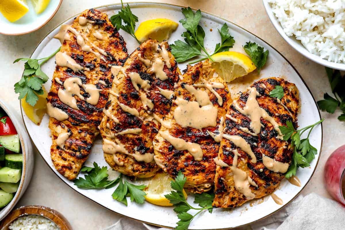 Chicken breasts on a serving platter with tahini sauce.