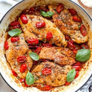 Tomato and basil chicken breasts in a pan.