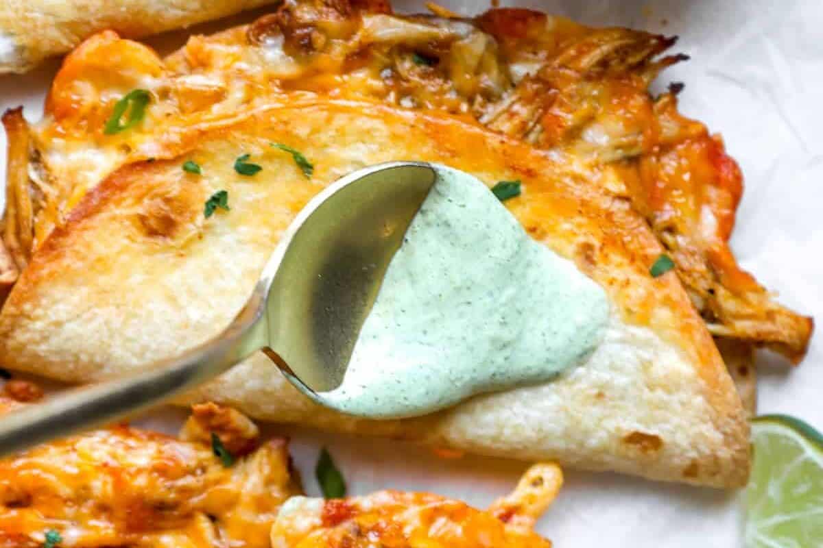 Spooning cilantro lime sauce onto a chicken taco.