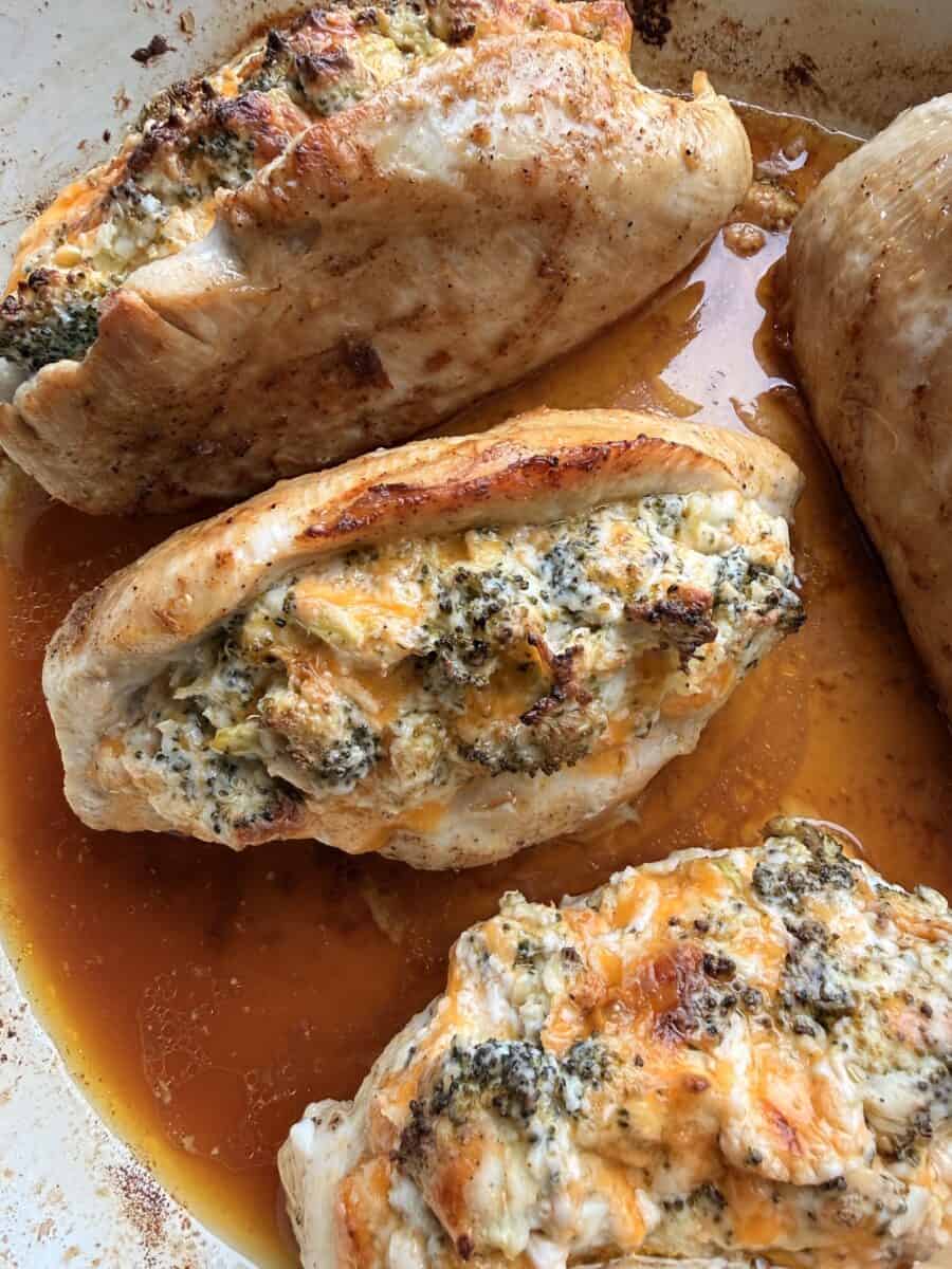 Cooking cheesy broccoli stuffed chicken in a pan.