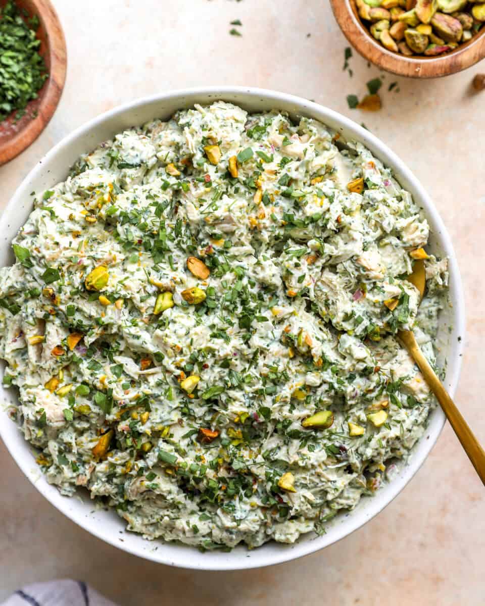 A bowl of green goddess chicken salad with pistachios.
