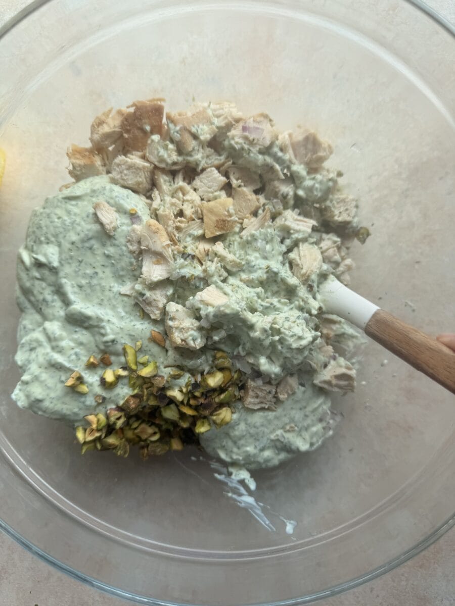 Mixing chicken salad ingredients with green goddess dressing.
