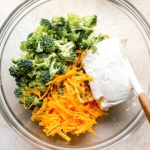 Broccoli, shredded cheddar, and cream cheese in a mixing bowl.