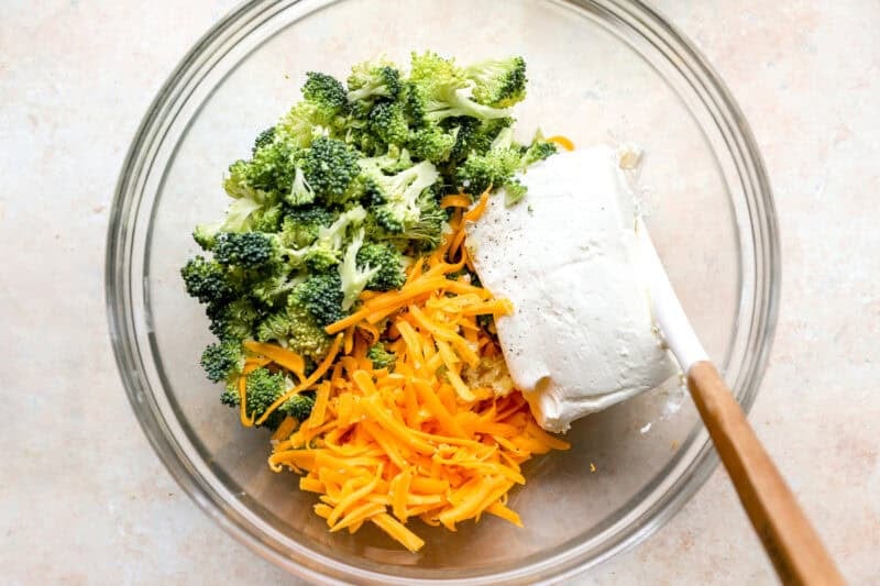 Broccoli, shredded cheddar, and cream cheese in a mixing bowl.