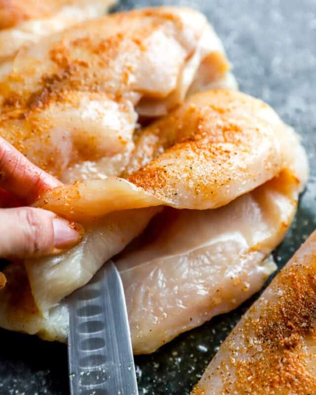 Cutting a pocket into the side of a chicken breast.